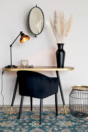 Moderner Beistelltisch mit goldener Tischplatte und schwarzen Beinen, seitliche Perspektive, dekoriert mit einer schwarzen Vase und einer Tischlampe.