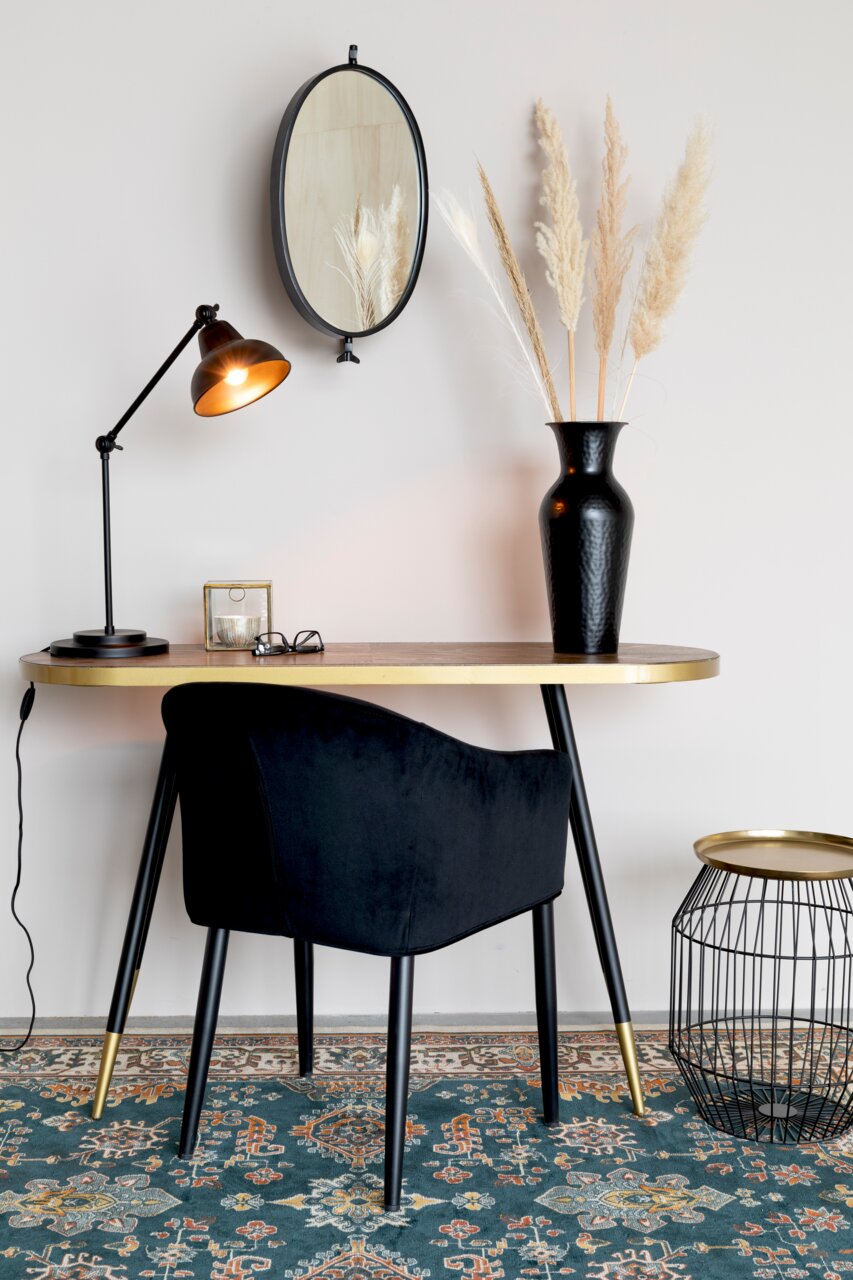 Moderner Beistelltisch mit goldener Tischplatte und schwarzen Beinen, seitliche Perspektive, dekoriert mit einer schwarzen Vase und einer Tischlampe.