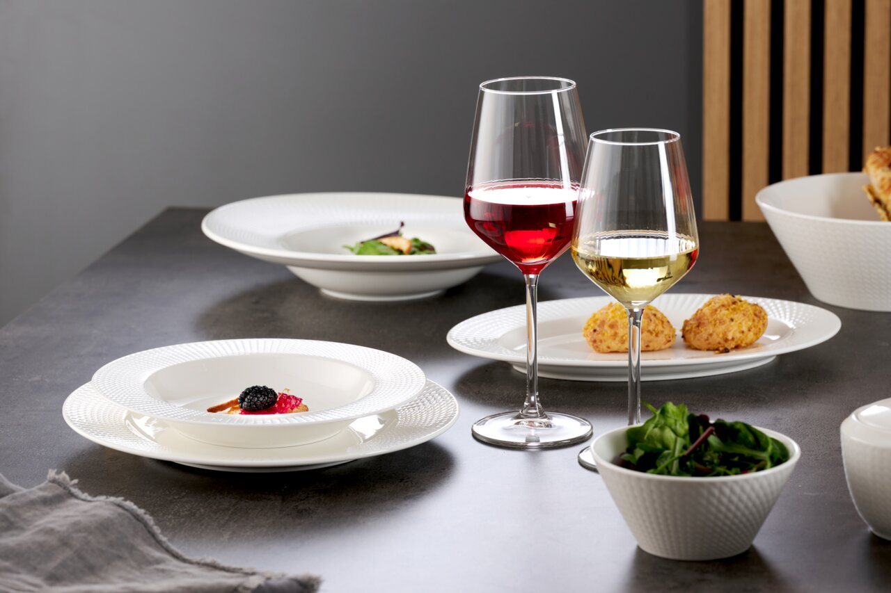 Ritzenhoff & Breker Speiseteller SAPHIR Elegante Speiseteller und Schalen in einem modernen Tischarrangement mit Rot- und Weißweingläsern, seitliche Perspektive.