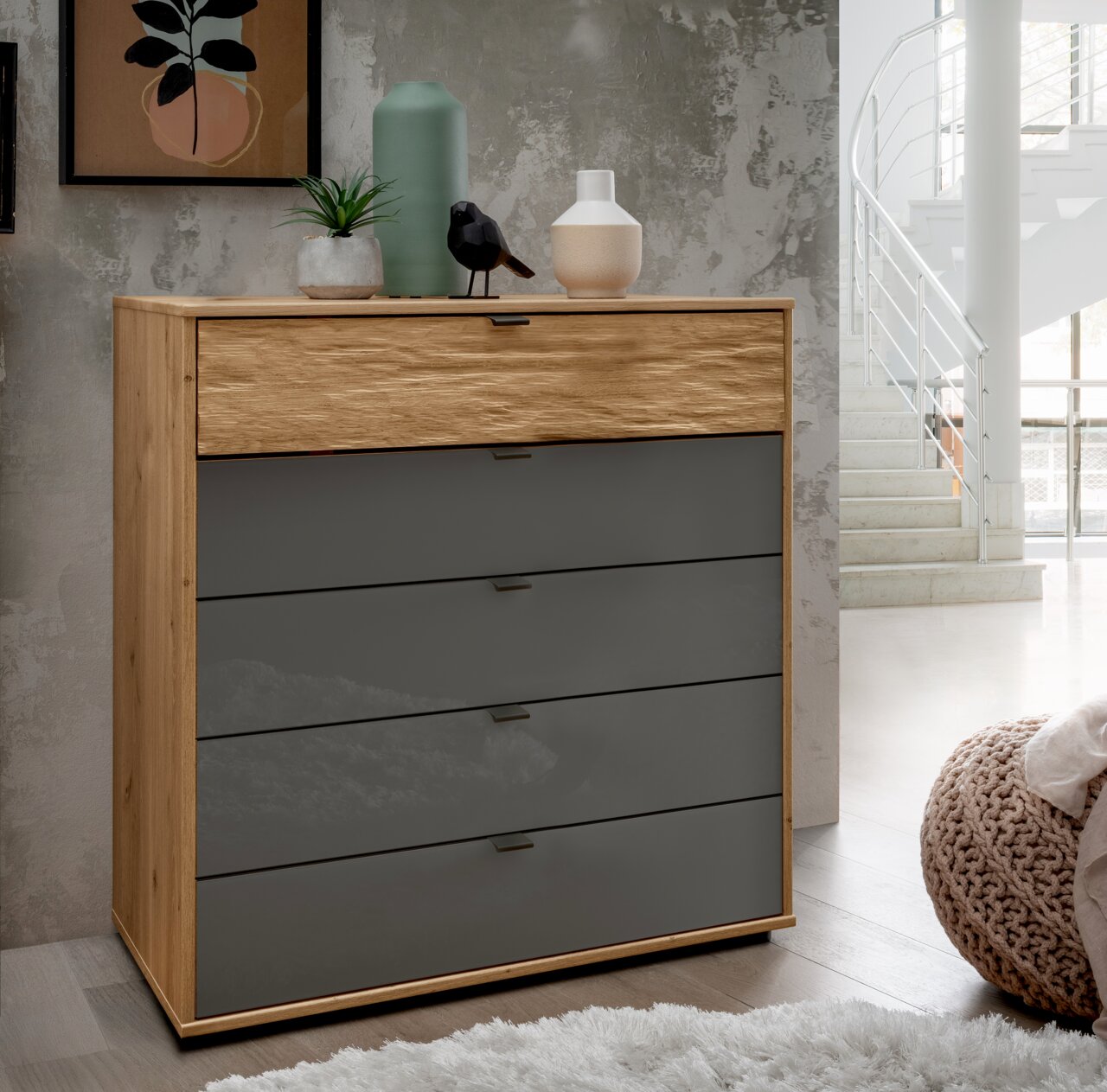 Moderne Schubkastenkommode aus Holz mit grauen Schubladen, dekoriert mit Pflanzen und Vasen, seitliche Perspektive