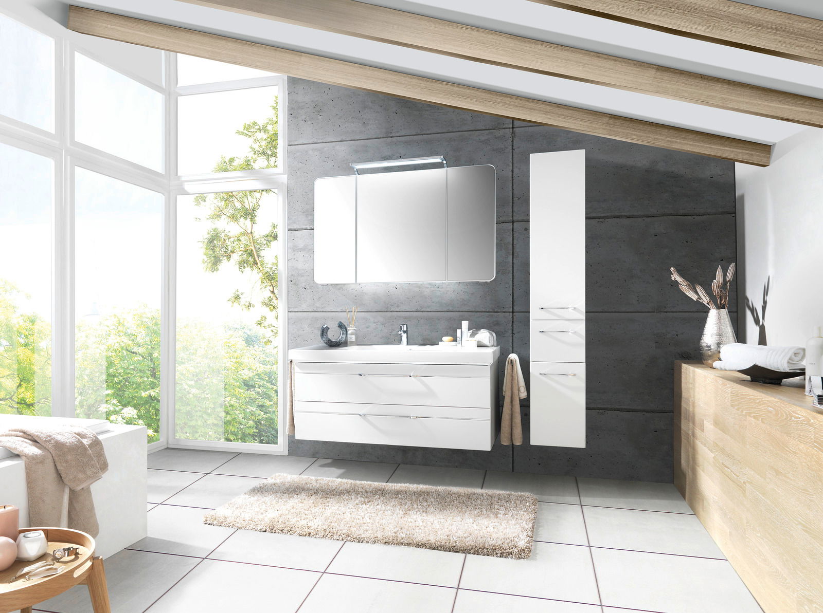 Moderne Badkombination mit weißem Waschtisch und Spiegelschrank, seitlich von einem hohen Schrank flankiert, in einem hellen Badezimmer mit großen Fenstern und Holzbalkendecke, Perspektive von vorne.