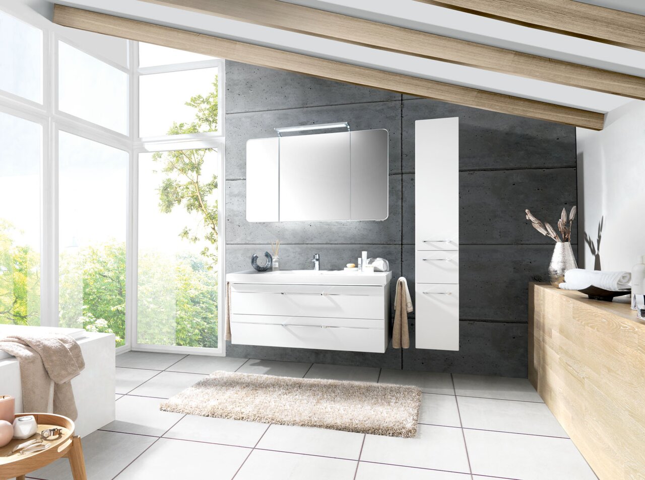Moderne Badkombination mit weißem Waschtisch und Spiegelschrank, seitlich von einem hohen Schrank flankiert, in einem hellen Badezimmer mit großen Fenstern und Holzbalkendecke, Perspektive von vorne.