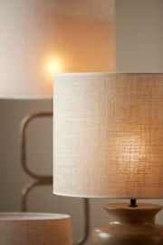 Nahaufnahme von zwei beleuchteten, beigen Lampenschirmen aus Stoff in einem warmen Raum.