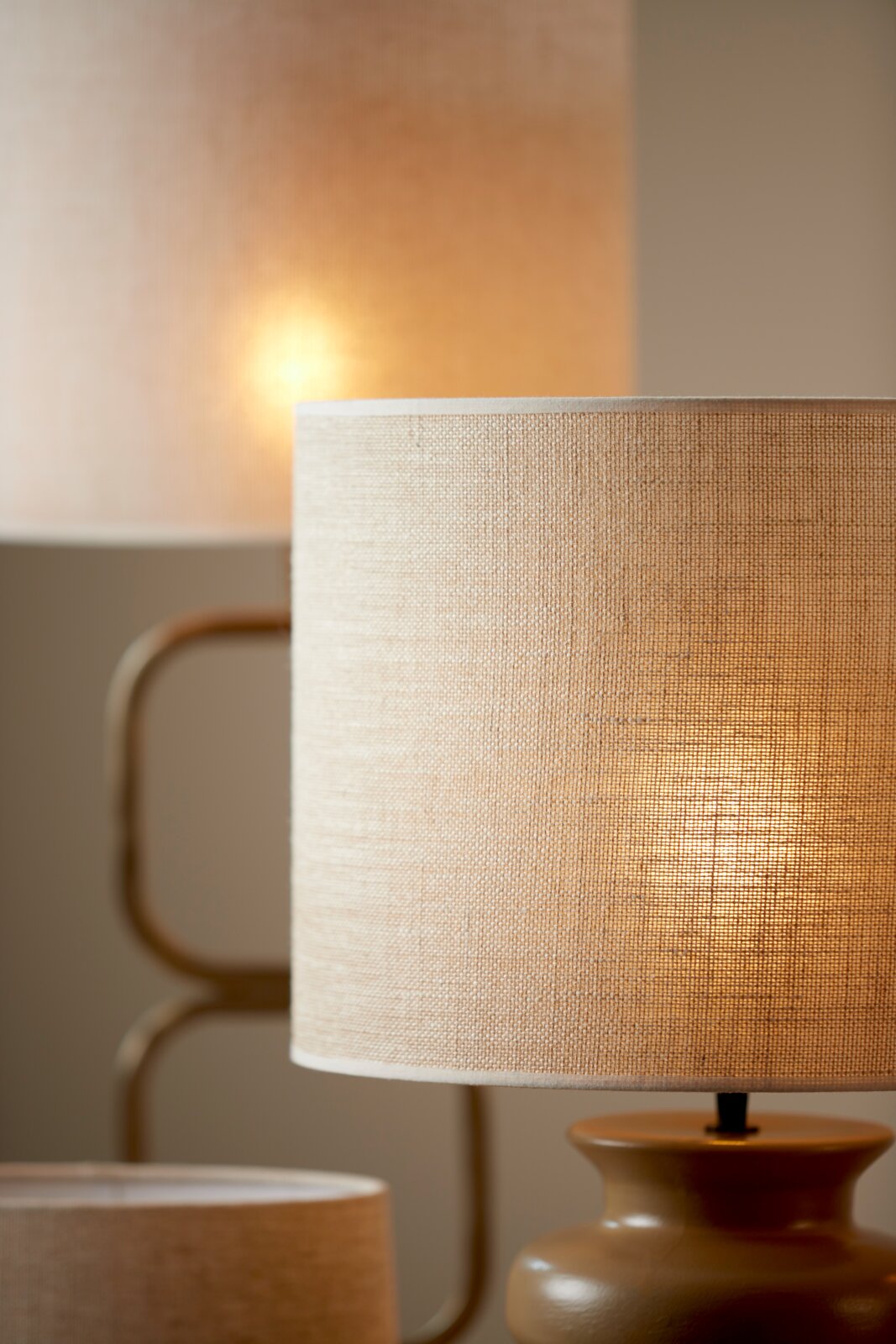 Close-up van twee verlichte, beige stoffen lampenkappen in een gezellige kamer.