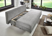 Graues Funktionssofa in moderner Wohnzimmereinrichtung, von schräg oben fotografiert, mit ausgezogenem Bettmechanismus.
