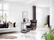 Moderner Relaxsessel mit schwarzem Lederbezug und Holzdetails, seitliche Perspektive im hellen Wohnzimmer