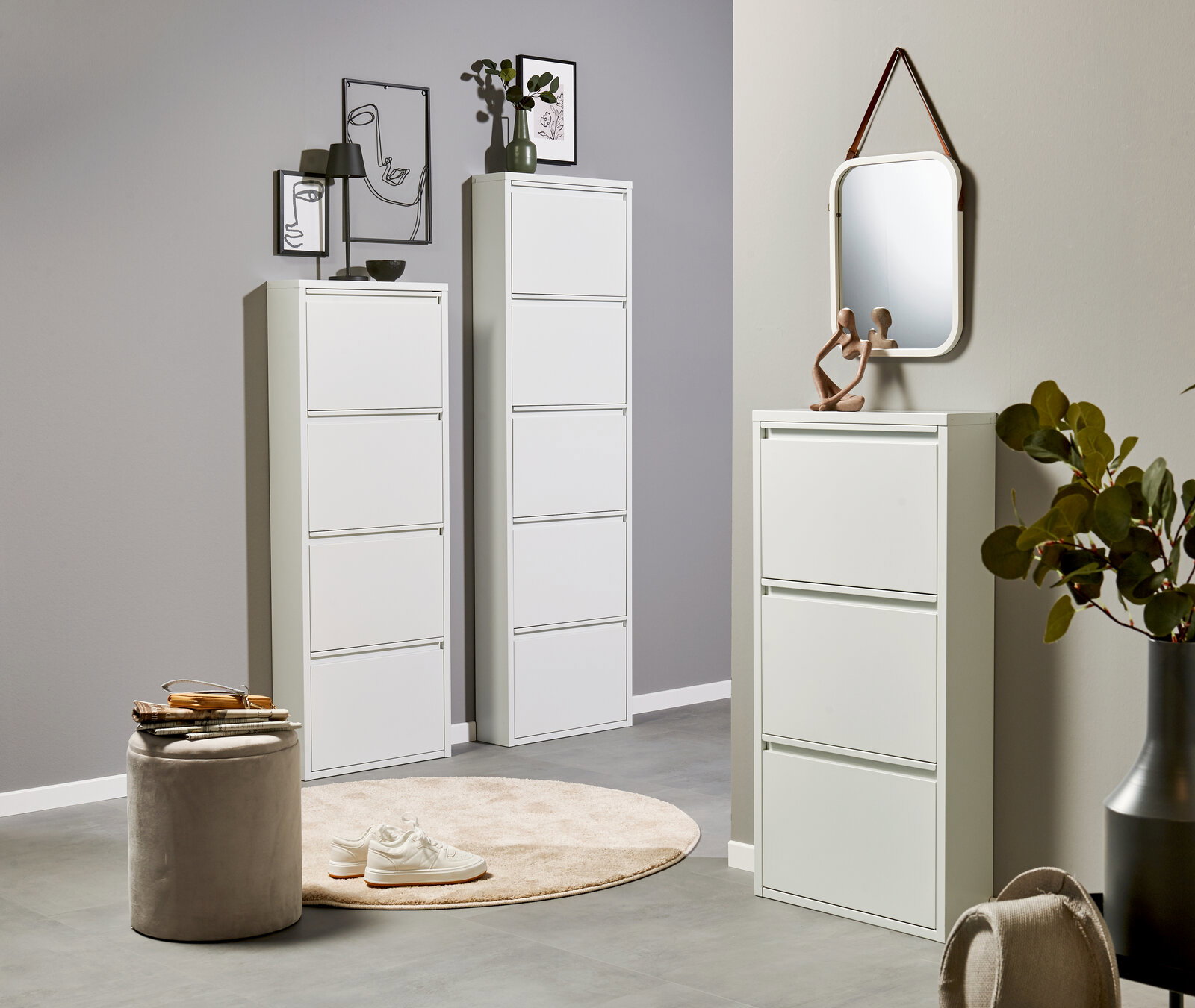 Modernes weißes Schuhkipper-Set im Flur: zwei hohe, schmale Schränke und ein niedriger Schuhschrank mit Spiegel darüber, frontal aus leicht seitlicher Perspektive fotografiert.