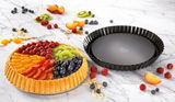 Obstkuchenform 28cm BackFreude, seitliche Perspektive, neben einem dekorierten Obstkuchen mit frischen Früchten auf einem Marmortisch.