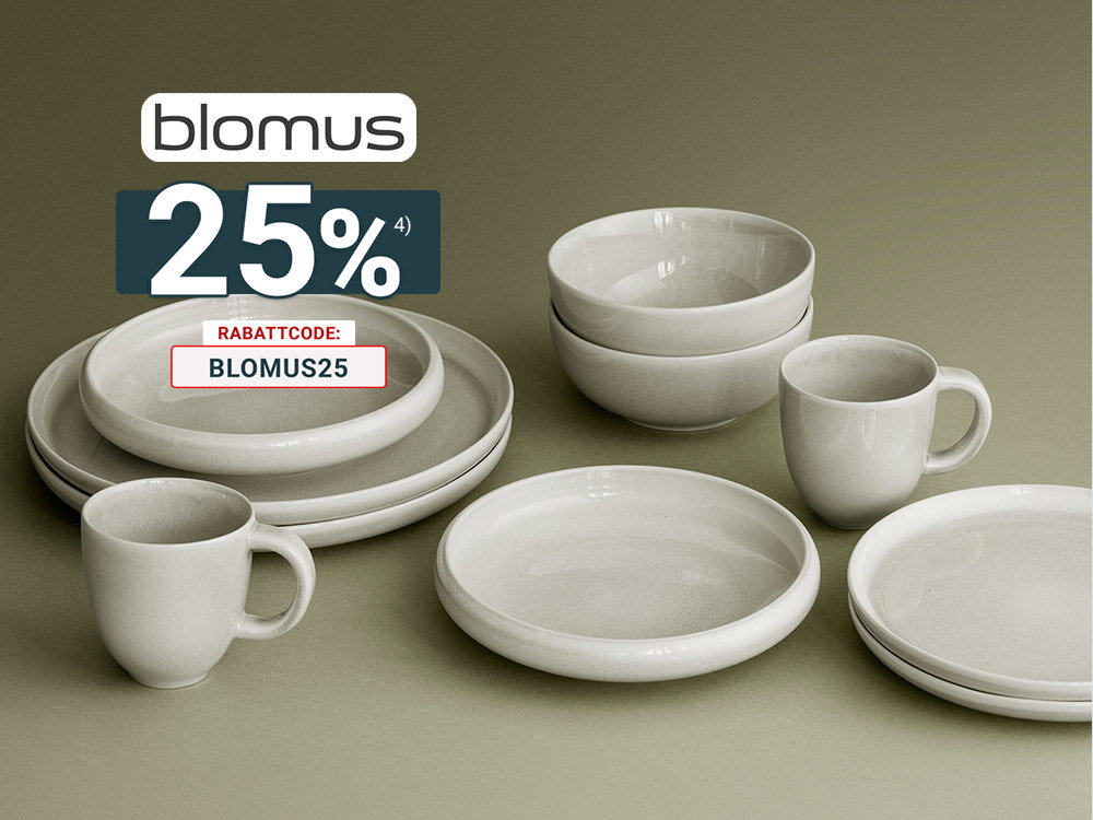 Helles Blomus-Geschirr mit Tellern, Schalen und Tassen in natürlicher Keramikoptik auf olivgrünem Hintergrund.