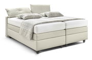 Boxspringbett QLX BKA in hellem Beige, seitliche Perspektive, mit zwei Kissen und einer gemusterten Decke.