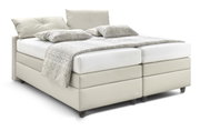 Boxspringbed QLX BKA in lichtbeige, zijaanzicht, met twee kussens en een gedessineerde deken.