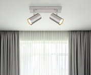 Moderne plafondspots van geborsteld metaal met twee verstelbare lampen, gezien van onderaf.