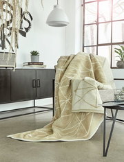 Beige Jacquard-Decke 150x200 cm auf einem Sessel in einem modernen Wohnzimmer, seitliche Perspektive