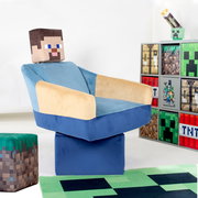 Minecraft-inspirierter Kinder-Sessel in Blau und Beige mit pixeligem Kopfkissen, schräg von vorne links fotografiert, neben einem Regal mit Minecraft-Motiven auf weißem Hintergrund