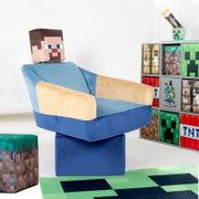 Minecraft-inspirierter Kinder-Sessel in Blau und Beige mit pixeligem Kopfkissen, schräg von vorne links fotografiert, neben einem Regal mit Minecraft-Motiven auf weißem Hintergrund