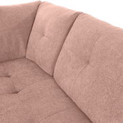 Nahaufnahme einer rosa gepolsterten Sofaecke mit weicher Textur und Steppnähten, Perspektive von oben.