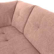 Nahaufnahme einer rosa gepolsterten Sofaecke mit weicher Textur und Steppnähten, Perspektive von oben.