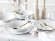 Elegant gedeckter Tisch mit weißen geriffelten Tellern und Schalen, goldfarbenem Besteck, Weinglas und Wasserglas sowie hellen Holz-Kerzenhaltern; Perspektive: leicht schräge Ansicht von oben.