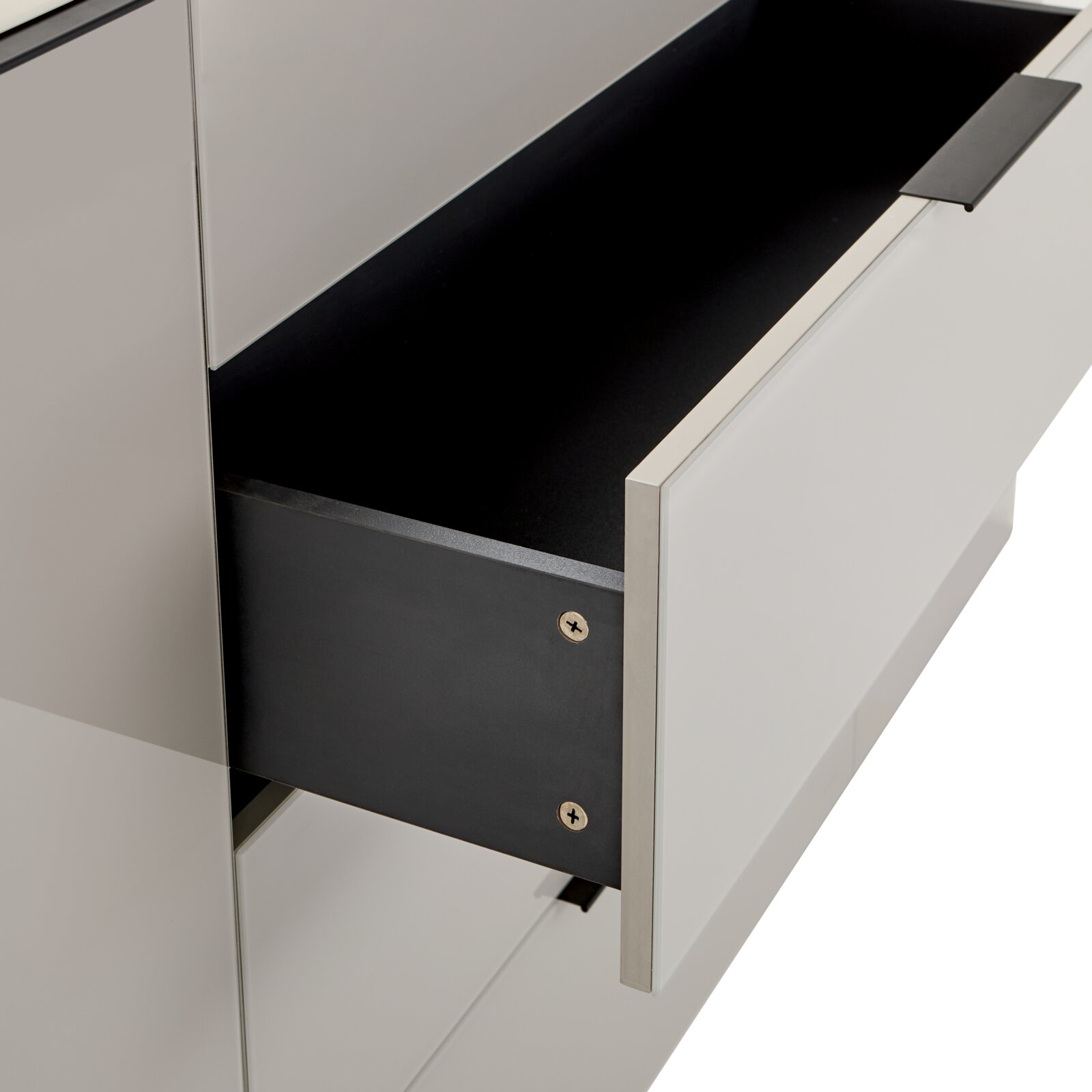 Nahaufnahme eines geöffneten Schubkastens in einem weißen Schrank/Sideboard mit schwarzem Innenraum und schwarzem Griff, schräg von vorne/rechts fotografiert