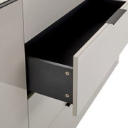 Nahaufnahme eines geöffneten Schubkastens in einem weißen Schrank/Sideboard mit schwarzem Innenraum und schwarzem Griff, schräg von vorne/rechts fotografiert