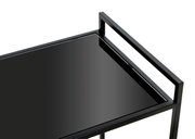 Close-up van een modern zwart bijzettafeltje met glazen blad, gezien van bovenaf.