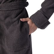 Nahaufnahme eines grauen Kapuzenbademantels in Größe M, mit einer Hand in der Tasche und einem Gürtel um die Taille, seitliche Perspektive.