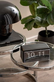 Moderne Flip-Uhr auf einem runden Glastisch, seitliche Perspektive.