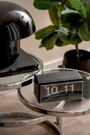 Moderne Flip-Uhr auf einem runden Glastisch, seitliche Perspektive.