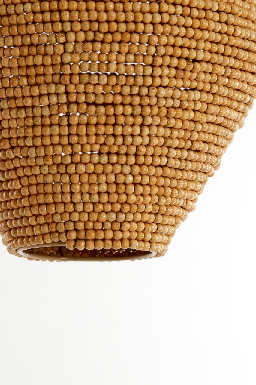 Close-up van een hanglamp met een oppervlak van kleine, ronde houten kraaltjes, gezien van onderaf.