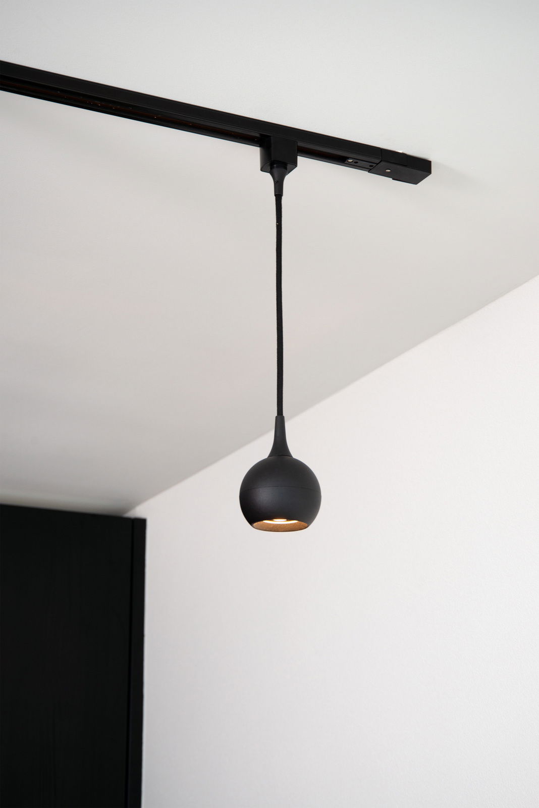 Schwarze Pendelleuchte FAVORI, kugelförmig, von der Decke hängend, seitliche Perspektive.