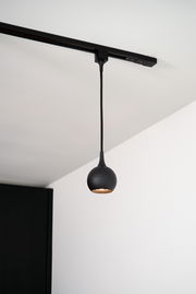 Schwarze Pendelleuchte FAVORI, kugelförmig, von der Decke hängend, seitliche Perspektive.