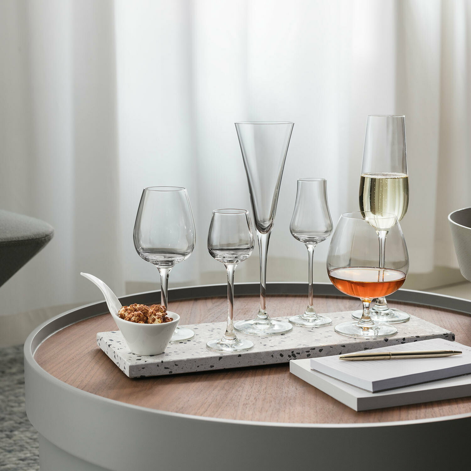 Villeroy & Boch Sektglas 4er-Set PURISMO Verschiedene Gläser, darunter Sektgläser, auf einem runden Tisch mit einer modernen, eleganten Präsentation aus der Seitenperspektive.
