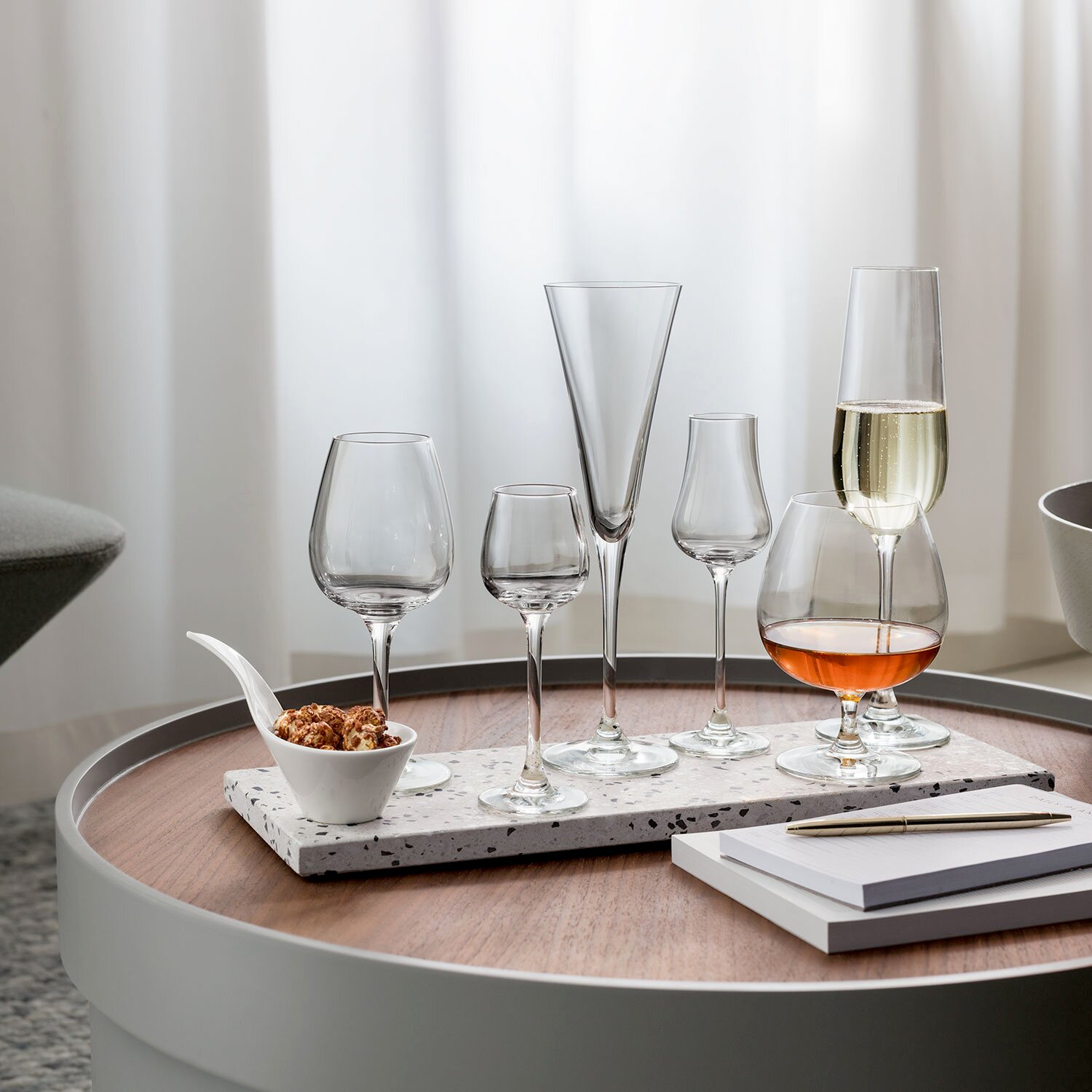 Villeroy & Boch Sektglas 4er-Set PURISMO Verschiedene Gläser, darunter Sektgläser, auf einem runden Tisch mit einer modernen, eleganten Präsentation aus der Seitenperspektive.