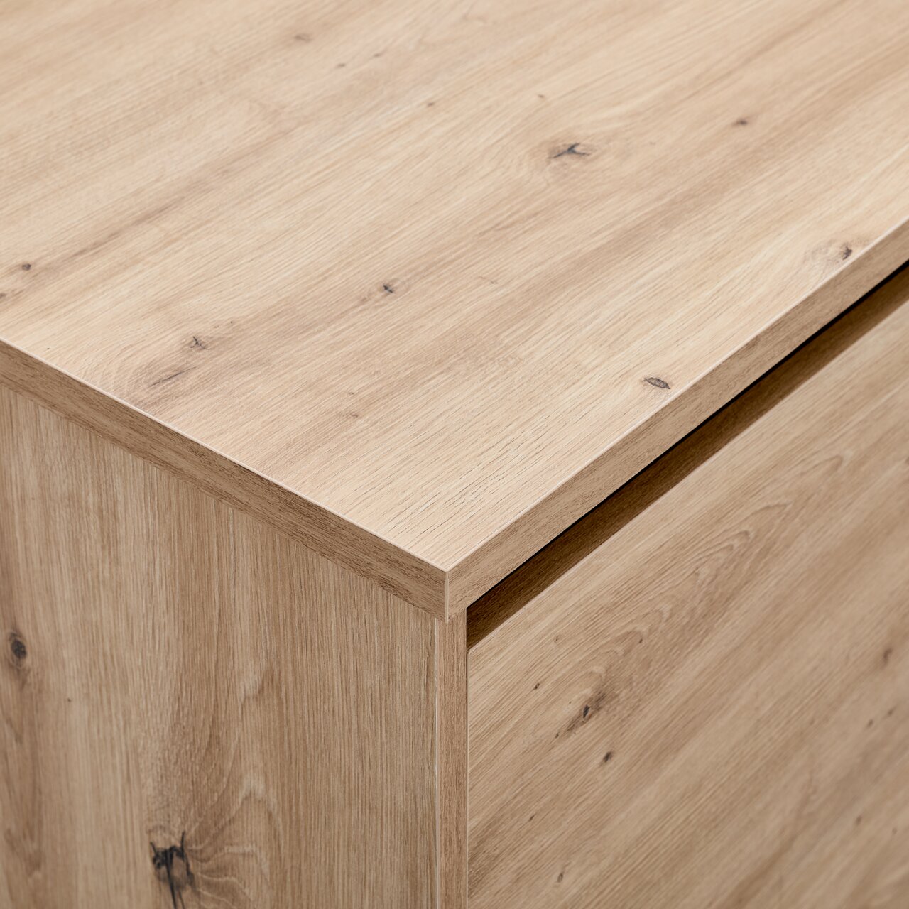 Nahaufnahme eines TV-Lowboards aus hellem Holz mit sichtbarer Maserung, Perspektive von oben.