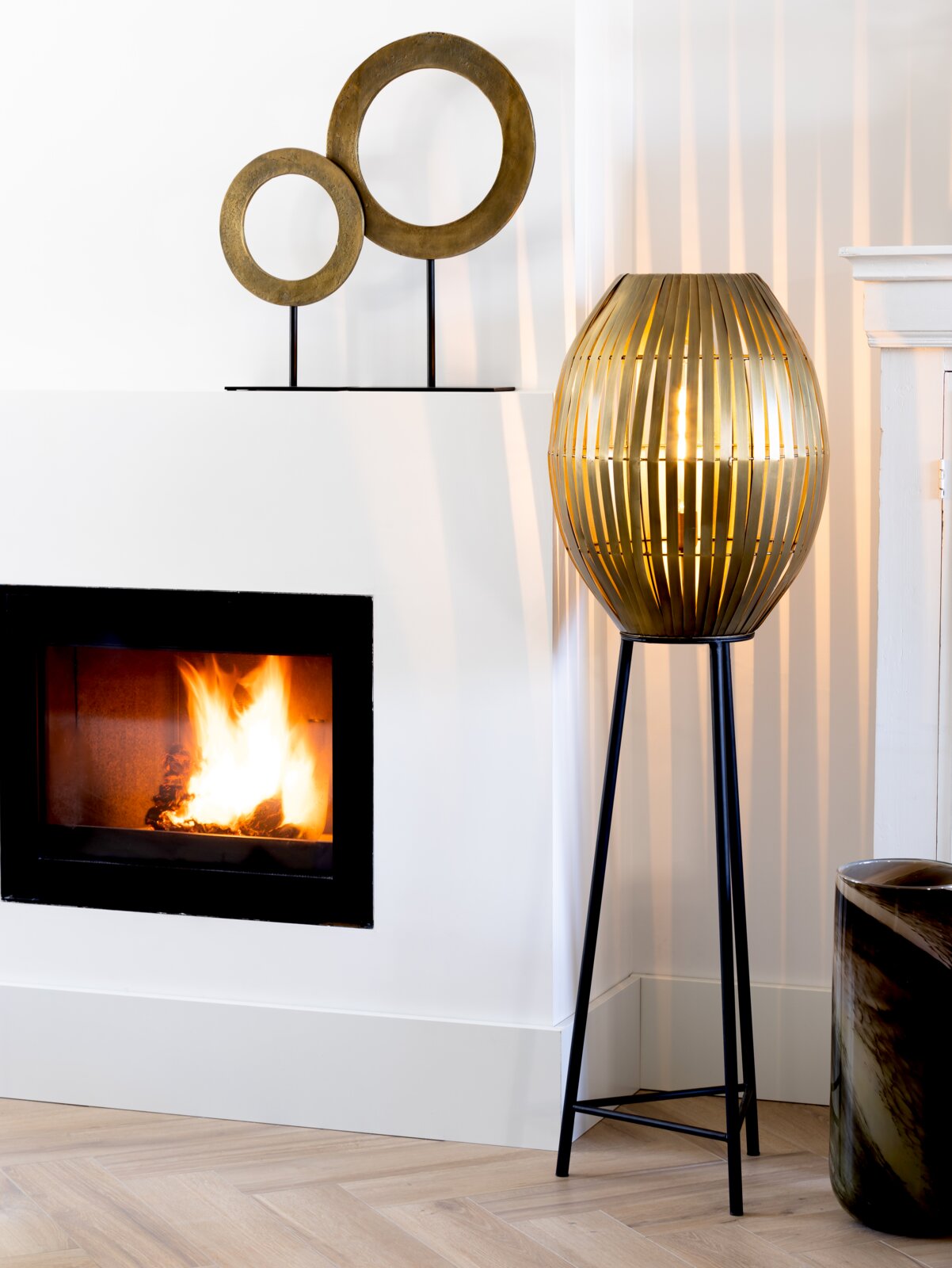 Decoratief ornament met twee in elkaar verstrengelde gouden ringen op een zwarte sokkel, gezien vanaf de zijkant.