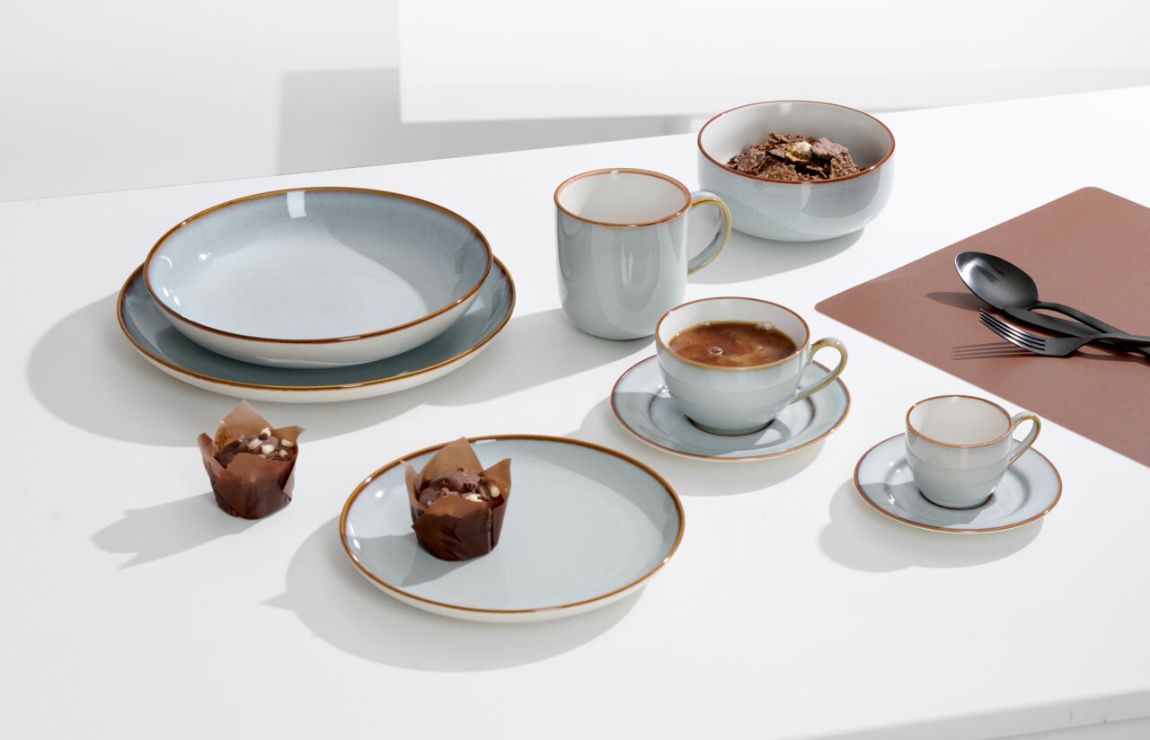 Ritzenhoff & Breker Speiseteller PORTOFINO Ein stilvoll gedeckter Tisch mit einem Speiseteller, Tassen, Schalen und Besteck in einer modernen, minimalistischen Ästhetik. Die Perspektive zeigt eine Draufsicht auf das Geschirrset.