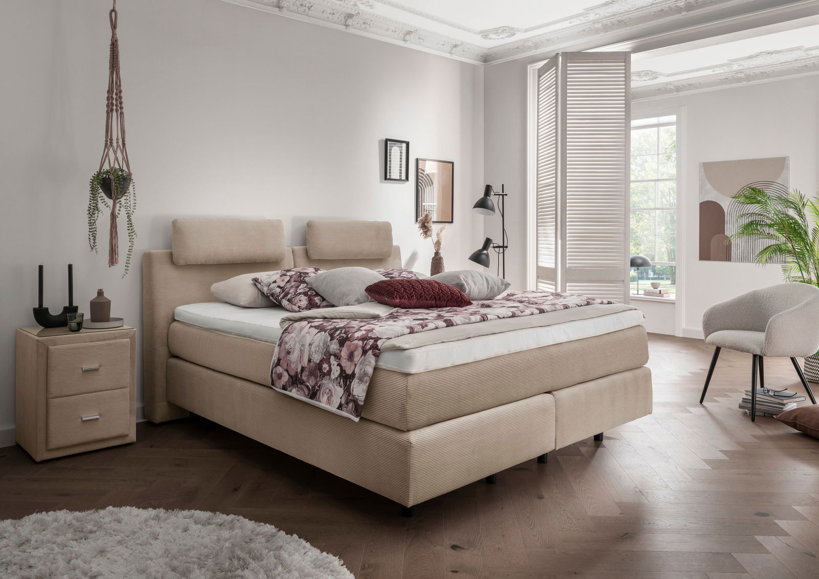 Gemütliches Boxspringbett in einem stilvoll eingerichteten Schlafzimmer, seitliche Perspektive.