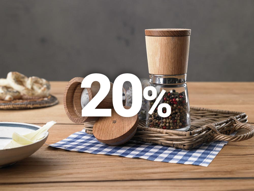 Eine Pfeffermühle mit Holzaufsatz liegt auf einem blau karierten Tuch und mit einem „20%“-Rabatttext im Vordergrund.