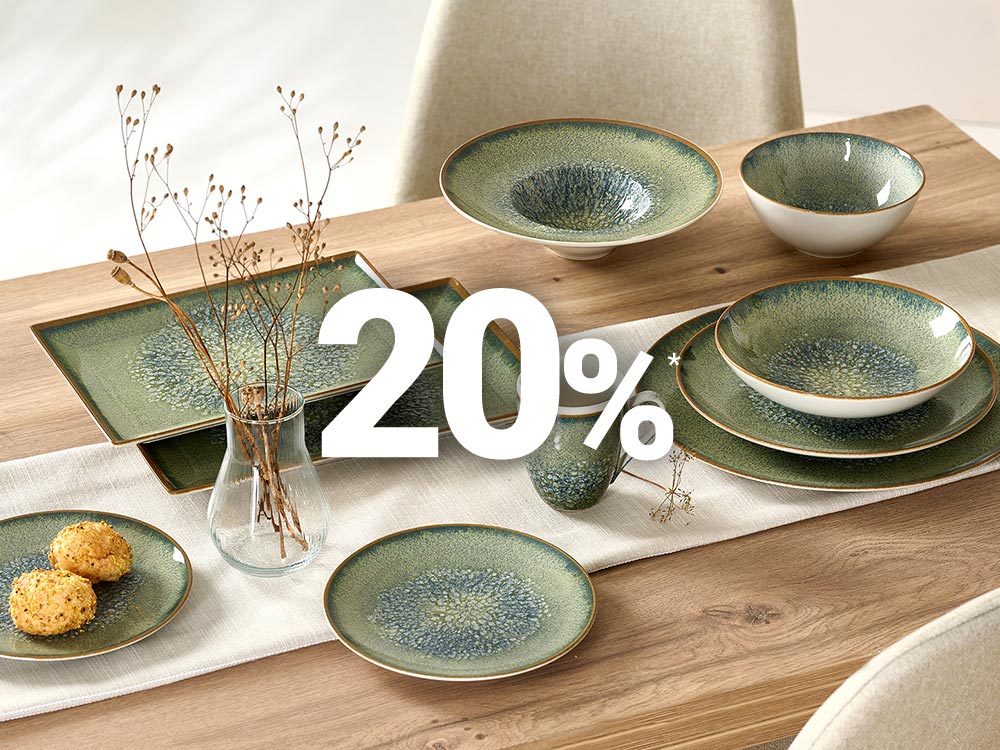 Grünes Keramikgeschirr auf Holztisch mit 20 % Rabatt.