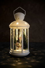 LED-Laterne mit winterlicher Szene, Schneemännern und Tannenbäumen, beleuchtet in dunkler Umgebung, seitliche Perspektive