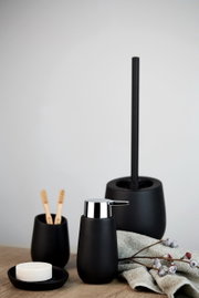 Keramik Seifenspender Badi in mattem Schwarz, frontal fotografiert, neben passendem Zahnbürstenhalter und Toilettenbürste auf einem Holztisch.