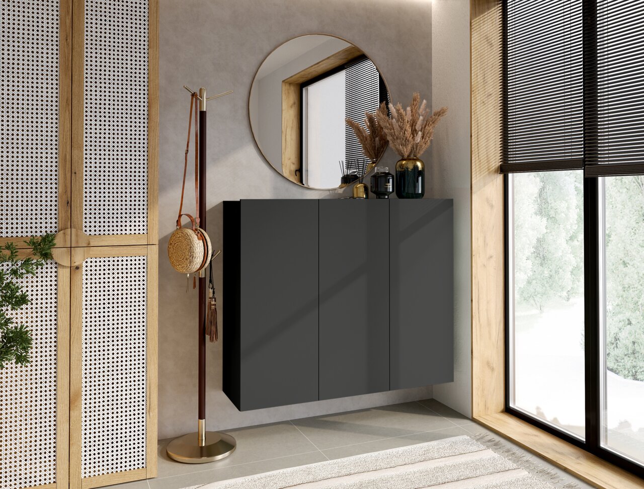 Hom´in Hängeschuhschrank NEWNIQ Moderner Hängeschuhschrank in dunklem Design, frontal betrachtet, mit dekorativen Elementen auf der Oberseite, neben einem großen Fenster und einem runden Spiegel.