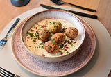 Orientalisches Gericht mit knusprigen Falafel-Bällchen auf Joghurt-Minz-Dip, garniert mit Granatapfel und Kräutern