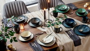 Een elegant 10-delig servies in verschillende kleuren op een feestelijk gedekte tafel, gefotografeerd van bovenaf.