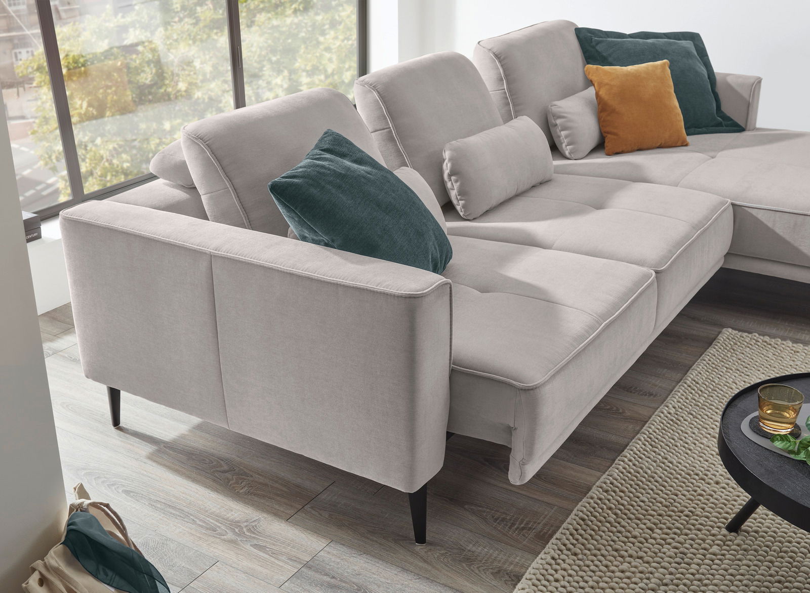 Graues Ecksofa mit mehreren Kissen in verschiedenen Farben, seitliche Perspektive.