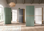 Moderne Schrank-/Garderobenschränke in Grün, Weiß und Anthrazit mit Holzdetails in einem hellen Raum, frontale Perspektive auf die Möbelgruppe