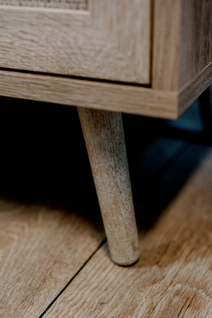 Nahaufnahme eines Holzbeins eines Möbelstücks, das auf einem Holzboden steht. Perspektive von unten.