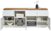 Frontale Ansicht eines weißen XL-Sideboards mit Holztop, offenen Schubladen und Türen, gefüllt mit Büchern, Schalen und Dekoration.
