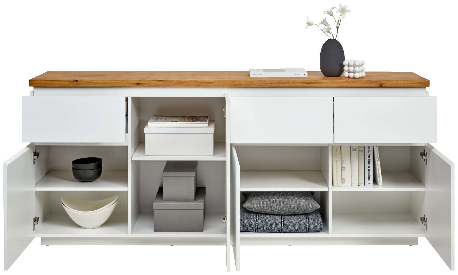 Frontale Ansicht eines weißen XL-Sideboards mit Holztop, offenen Schubladen und Türen, gefüllt mit Büchern, Schalen und Dekoration.