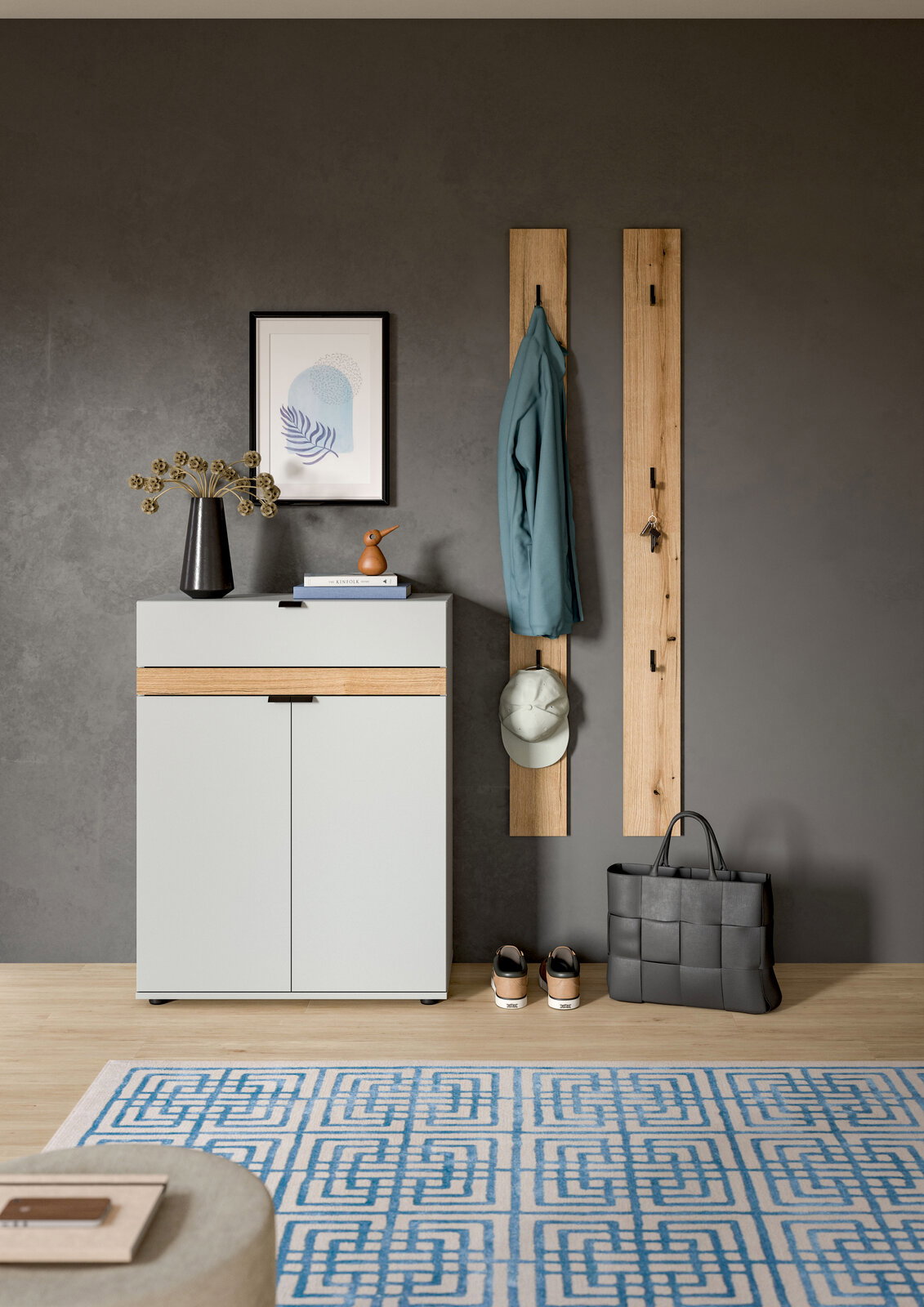 Modernes Flur-Set mit weißem Schuhschrank mit Holz-Akzent, zwei vertikalen Garderobenpaneelen aus Holz mit Haken, aufgehängter Jacke und Cap sowie Tasche und Schuhen auf grauer Wand, Frontansicht.
